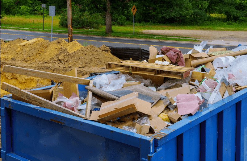 Dumpster full of construction debris in a yard