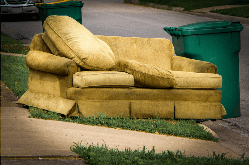 Couch sitting in yard by street waiting to be removed